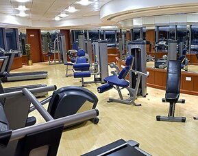Modern fitness center with treadmills, cardio machines, weight equipment, mirrored walls, and spacious workout areas.