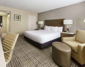 Contemporary king guest room featuring seating area, ottoman, work desk, and neutral-toned décor.