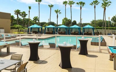 Poolside patio with cocktail tables, cabanas, lounge seating, and recreational games overlooking the pool.