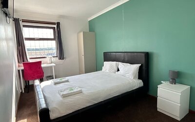 Bright guest room with double bed, work desk, wardrobe, and large window at Stay Inn Express.