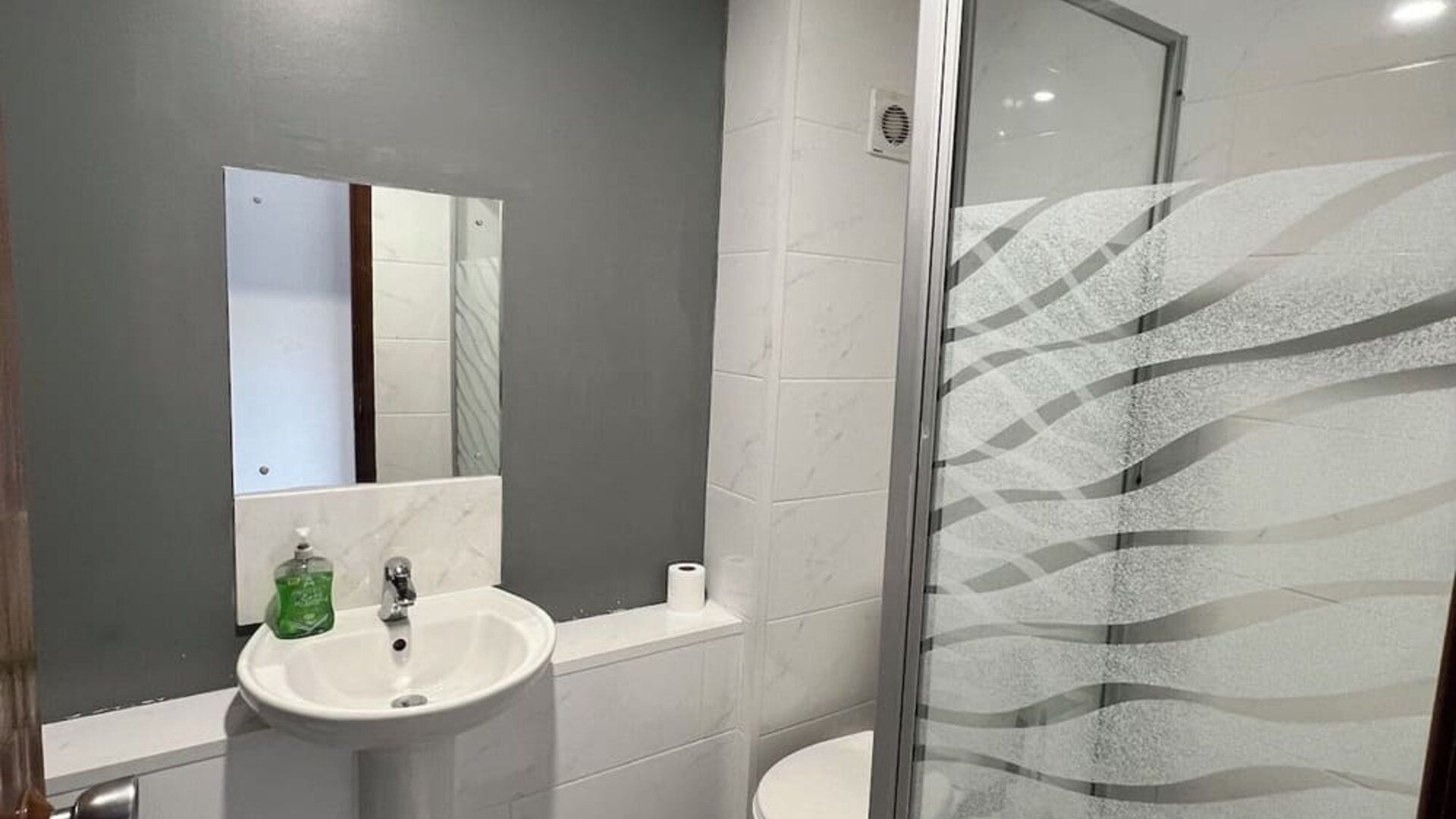 Bathroom with walk-in shower, pedestal sink, and modern finishes at Stay Inn Express.
