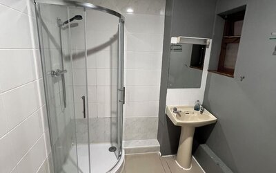 Bathroom with glass-enclosed shower, pedestal sink, and modern tiled design at Stay Inn Express.
