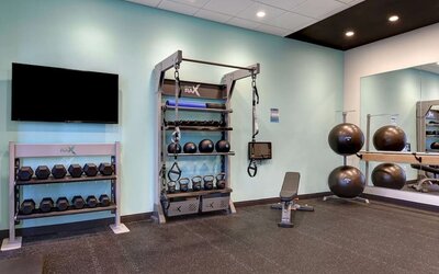 Modern fitness facility featuring dumbbells, kettlebells, suspension trainers, and exercise equipment at Tru By Hilton Lithia Springs.