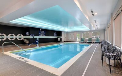 Indoor heated swimming pool with accessible lift, lounge chairs, and natural light at Tru By Hilton Lithia Springs.