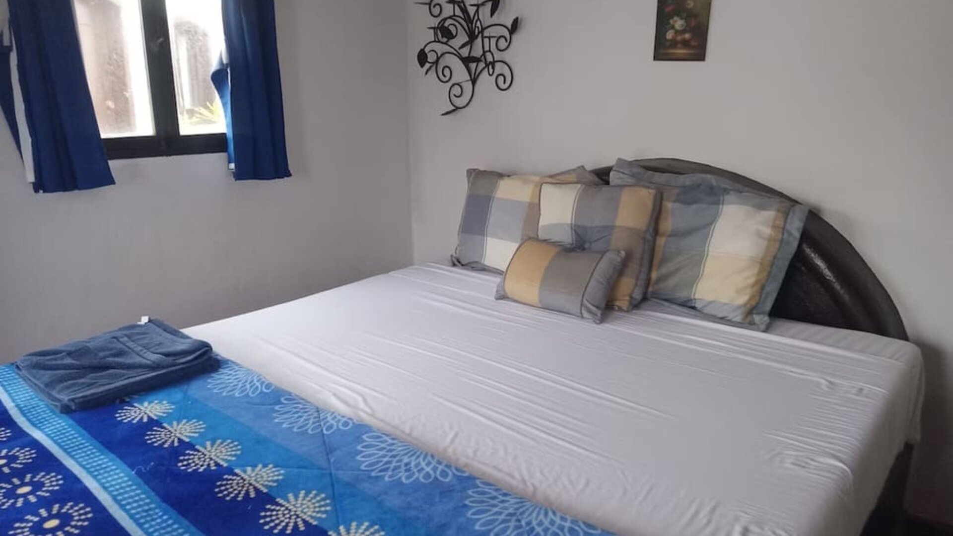 Cozy guest bedroom with queen-size bed, natural light, and charming coastal décor at Casa Playa Baja Resort.