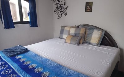 Cozy guest bedroom with queen-size bed, natural light, and charming coastal décor at Casa Playa Baja Resort.