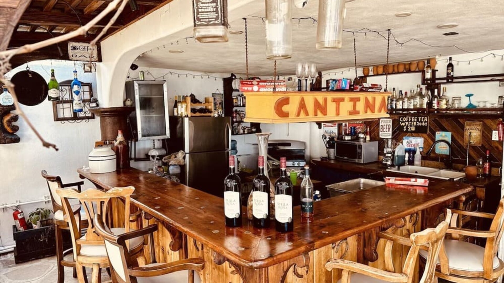 Rustic cantina-style bar with wooden seating, wine display, and beverage service at Casa Playa Baja Resort.