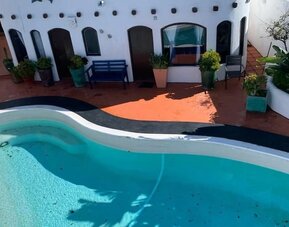 Outdoor swimming pool surrounded by resort accommodations and tropical landscaping at Casa Playa Baja Resort.