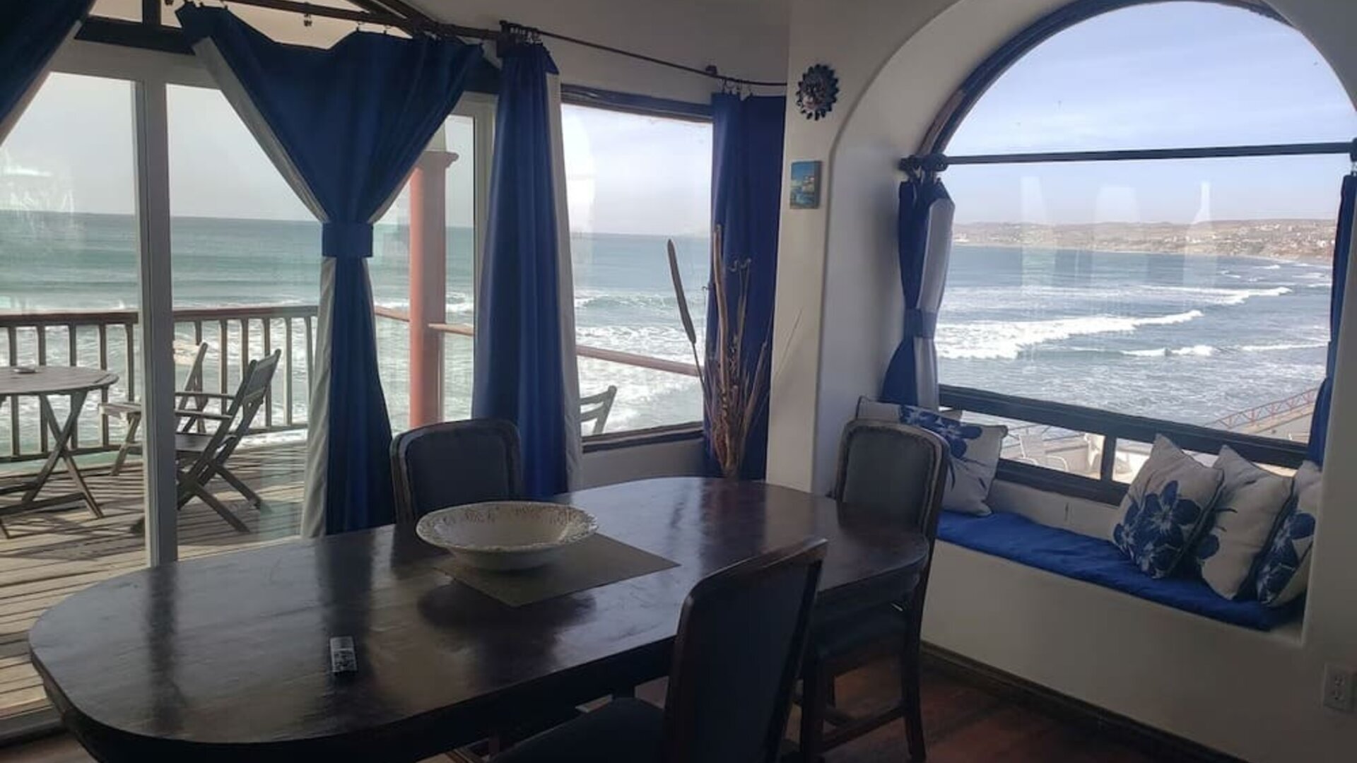 Dining area with panoramic ocean views, large windows, and access to a beachfront balcony at Casa Playa Baja Resort.