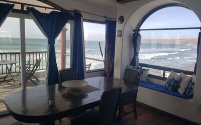 Dining area with panoramic ocean views, large windows, and access to a beachfront balcony at Casa Playa Baja Resort.