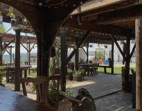 Open-air covered patio with rustic wooden seating and garden views at Casa Playa Baja Resort.