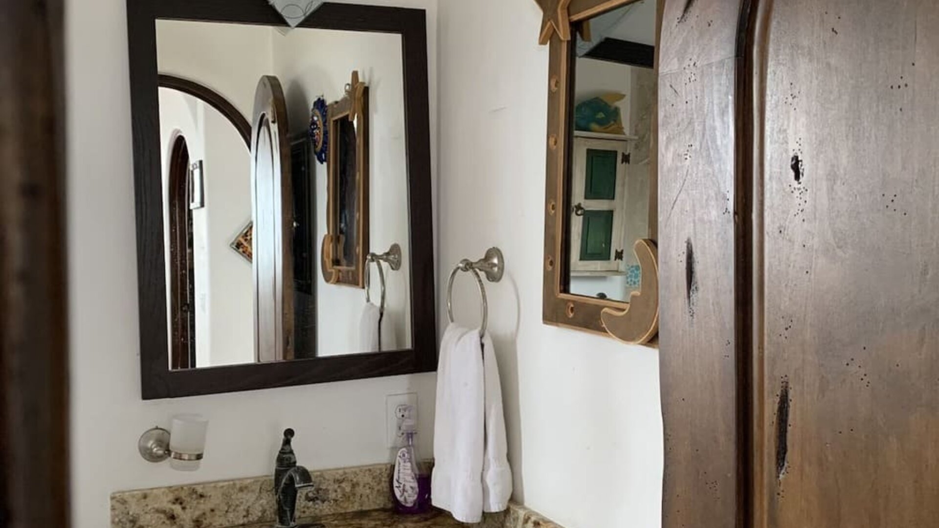 Bathroom vanity with granite countertop, sink, mirror, and rustic wood finishes at Casa Playa Baja Resort.