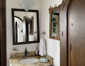 Bathroom vanity with granite countertop, sink, mirror, and rustic wood finishes at Casa Playa Baja Resort.