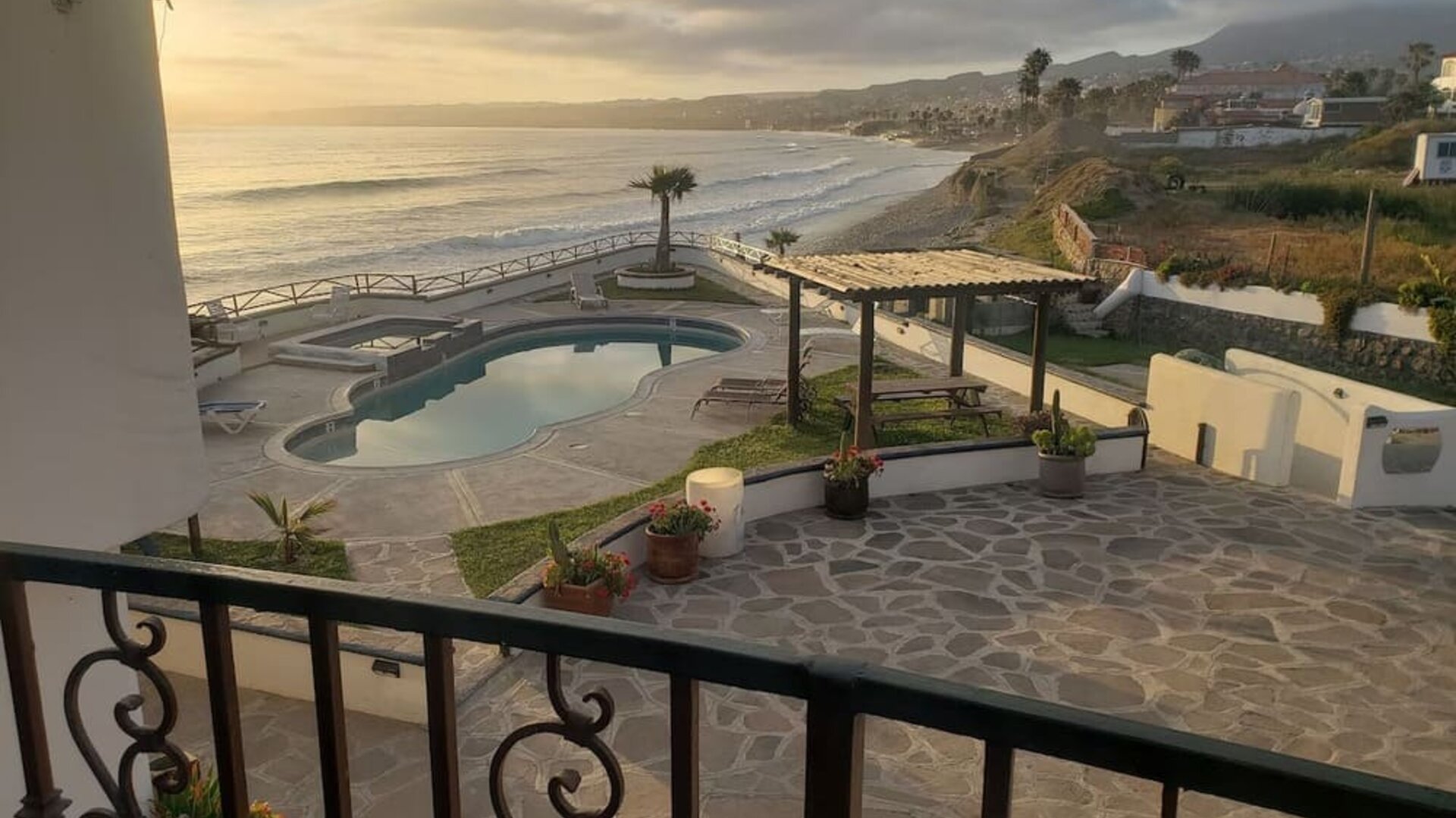 Balcony view of the resort grounds, swimming pool, and scenic coastline at Casa Playa Baja Resort.