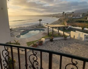 Balcony view of the resort grounds, swimming pool, and scenic coastline at Casa Playa Baja Resort.