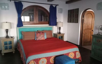 Spacious bedroom with king-size bed, rustic wood accents, exposed beams, and colorful décor at Casa Playa Baja Resort.
