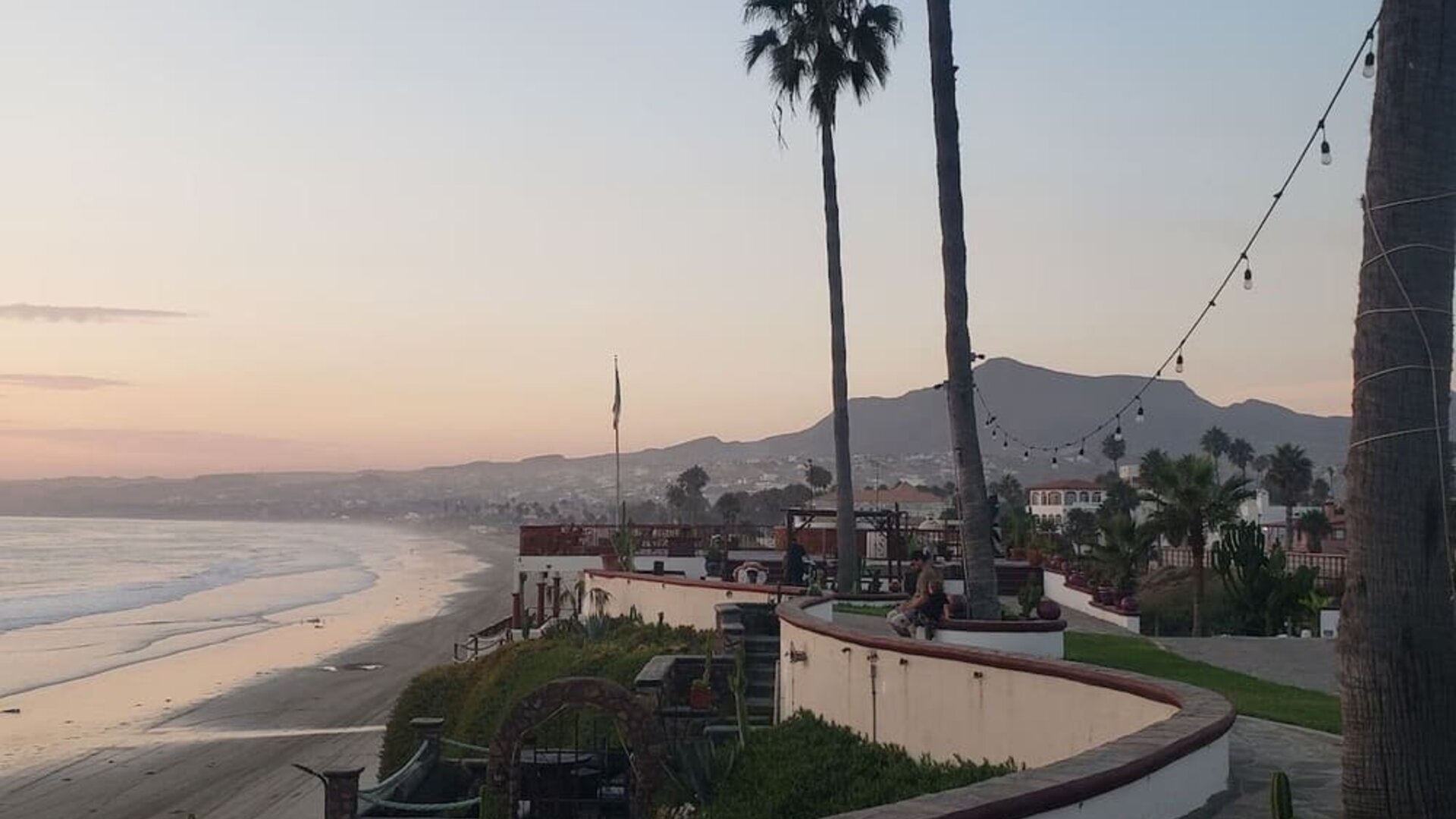 Scenic beachfront walkway lined with palm trees and panoramic coastline views at Casa Playa Baja Resort.