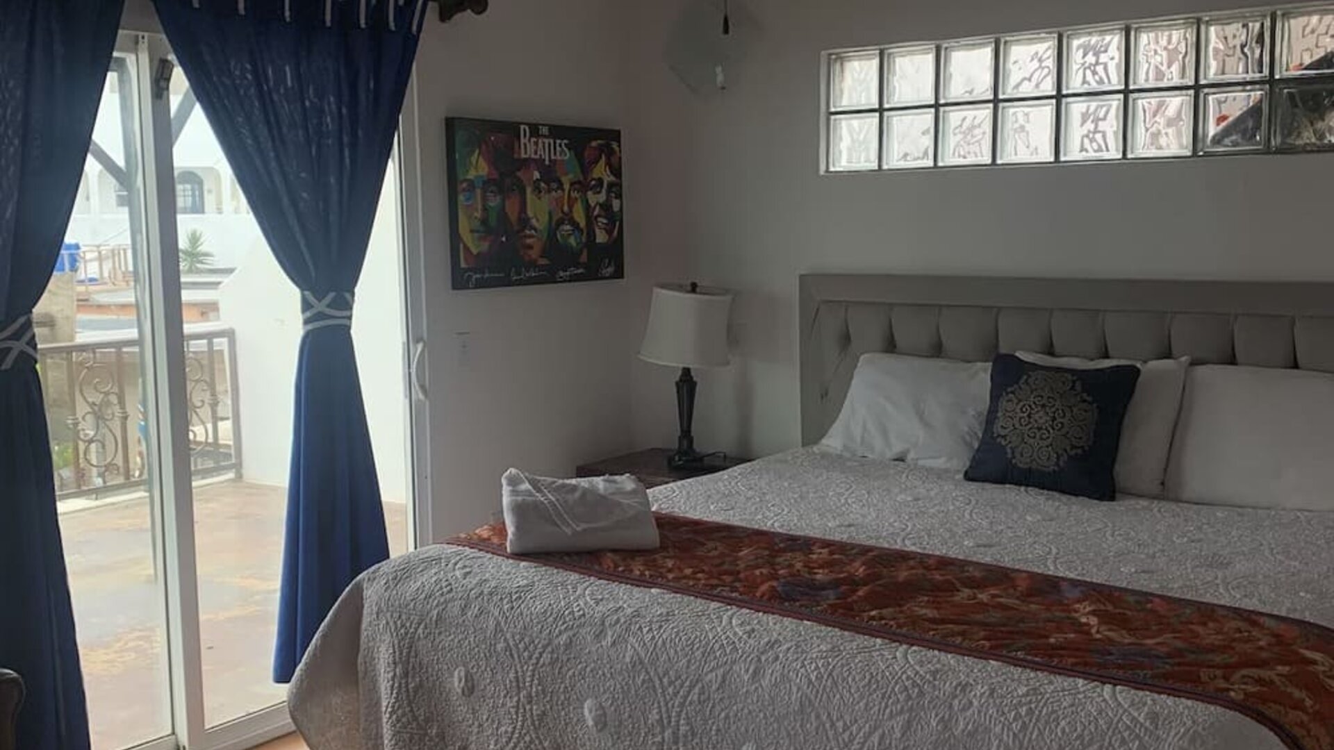 King bedroom with private balcony access, tiled floors, and comfortable seating at Casa Playa Baja Resort.