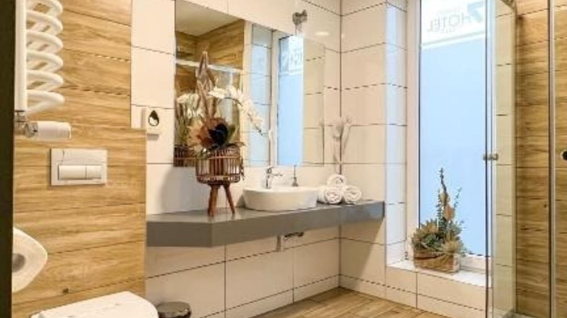 Modern hotel bathroom with walk-in glass shower, floating vanity and wood-effect tiles at Hotel Seven.