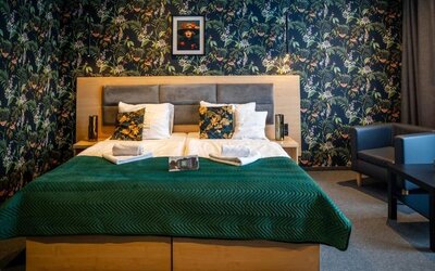 Stylish guest room with king-size bed, botanical feature wall and comfortable seating at Hotel Seven.