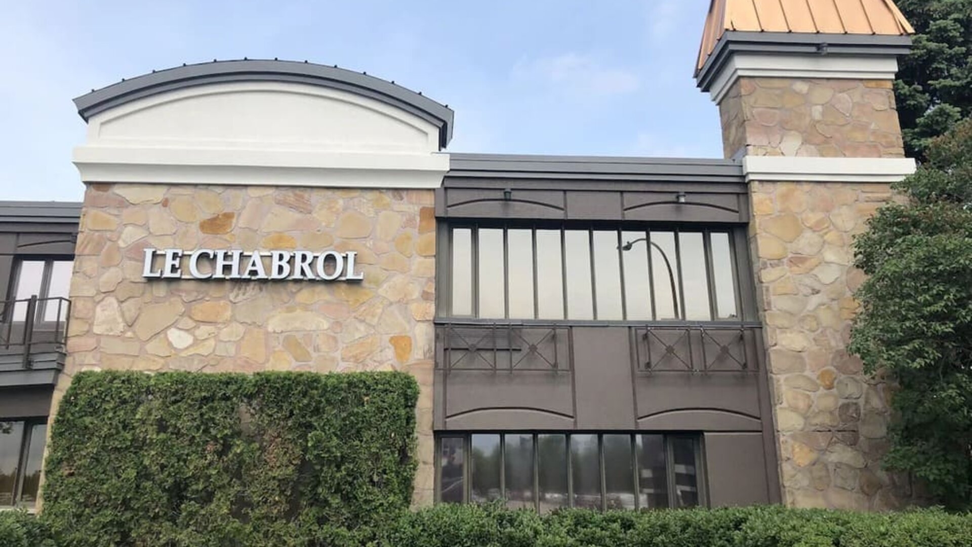 Exterior view of Le Chabrol Hotel Et Suites featuring its stone façade and main entrance.