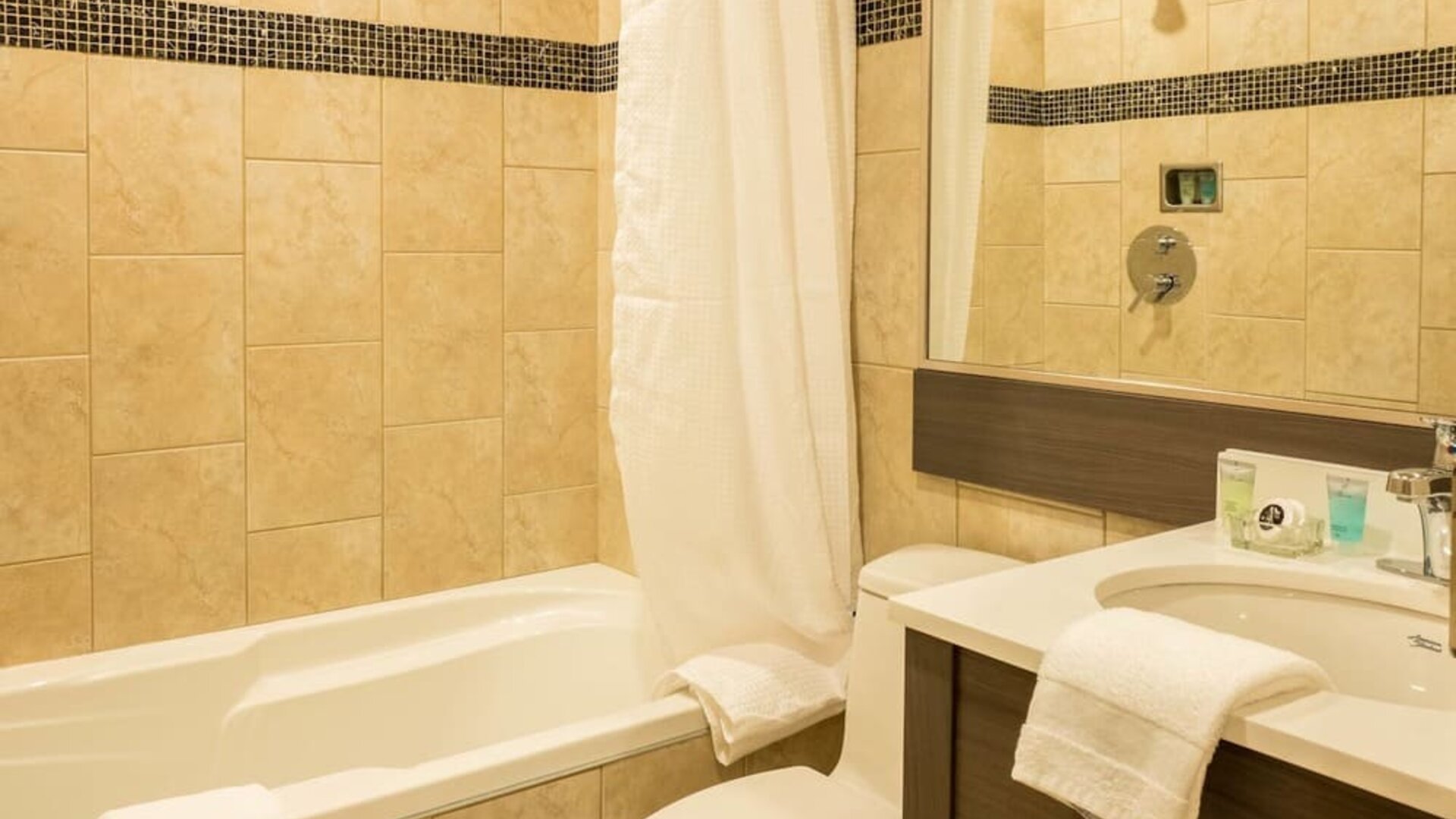 Contemporary guest bathroom featuring a bathtub, vanity and modern tiled finishes at Le Chabrol Hotel Et Suites.
