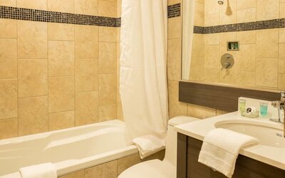 Contemporary guest bathroom featuring a bathtub, vanity and modern tiled finishes at Le Chabrol Hotel Et Suites.