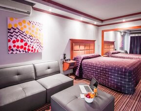Comfortable guest room with king-size bed, seating area and modern furnishings at Le Chabrol Hotel Et Suites.