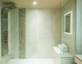 Luxury walk-in shower with rainfall showerhead and spa-inspired design at Le Chabrol Hotel Et Suites.