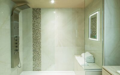 Luxury walk-in shower with rainfall showerhead and spa-inspired design at Le Chabrol Hotel Et Suites.