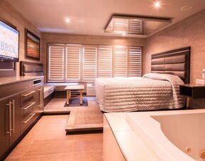 Spacious suite with king-size bed, in-room jacuzzi and seating area at Le Chabrol Hotel Et Suites.