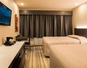 Comfortable twin guest room with workspace and modern amenities at Le Chabrol Hotel Et Suites.