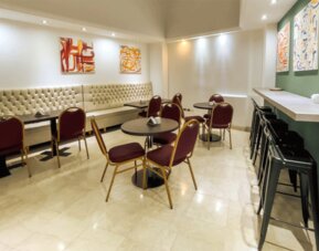 Additional dining and lounge space with café-style seating, upholstered banquettes, and contemporary artwork creating a relaxed atmosphere at HR Plaza Luxor.
