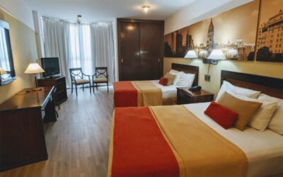 Alternative view of a guest room with two double beds, work area, flat-screen television, and warm décor designed for a comfortable stay in Buenos Aires at HR Plaza Luxor.