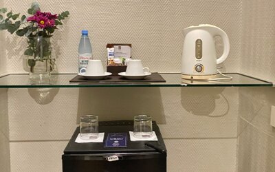 In-room refreshment station featuring complimentary bottled water, tea and coffee facilities, glassware, and a compact minibar for guest convenience at Hotel Lafayette.