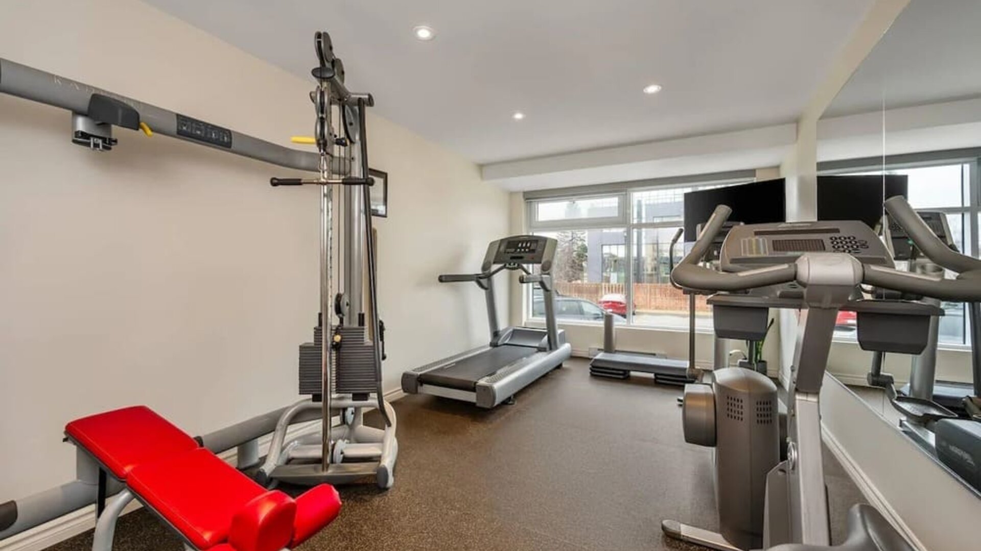 Modern fitness centre with cardio machines and strength training equipment at Hotel Brossard.