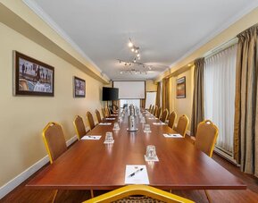 Spacious conference room with boardroom layout and audiovisual presentation facilities at Hotel Brossard.