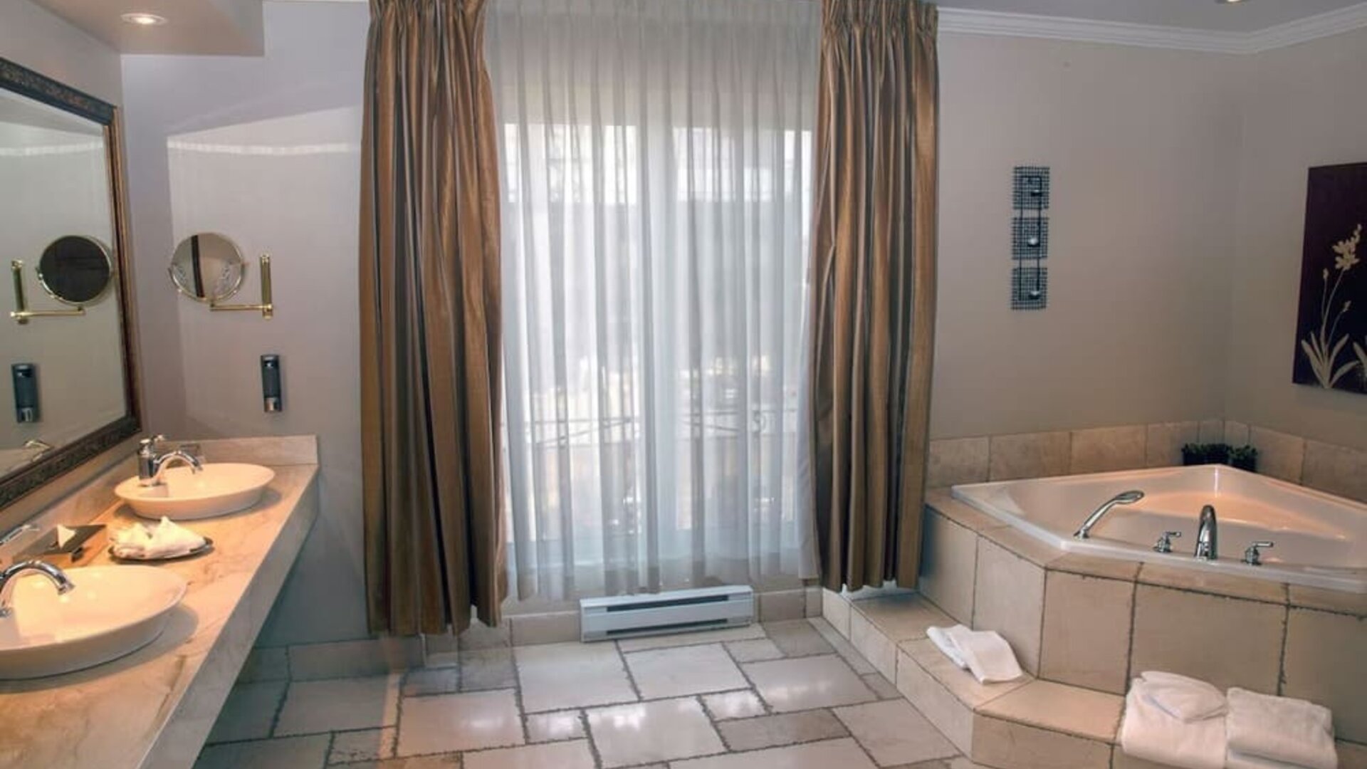 Luxury bathroom featuring a soaking tub, double vanity and spacious layout at Hotel Brossard.