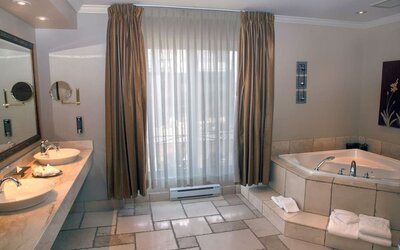 Luxury bathroom featuring a soaking tub, double vanity and spacious layout at Hotel Brossard.