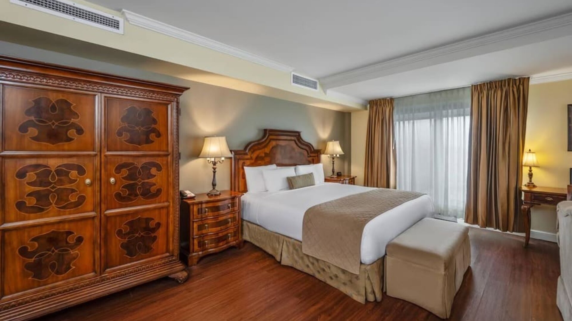 Comfortable king guest room with elegant furnishings and large wardrobe at Hotel Brossard.