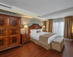 Comfortable king guest room with elegant furnishings and large wardrobe at Hotel Brossard.