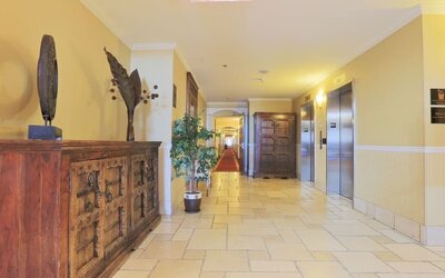 Bright hotel corridor with elevator access and elegant décor at Hotel Brossard.