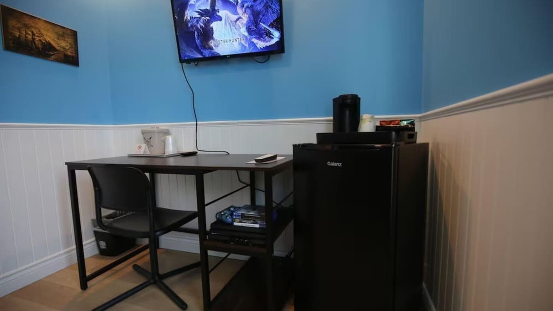 Dedicated guest workspace with desk, mini refrigerator and entertainment area at Hotel Brossard.