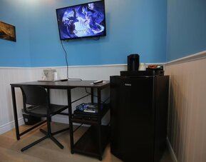 Dedicated guest workspace with desk, mini refrigerator and entertainment area at Hotel Brossard.