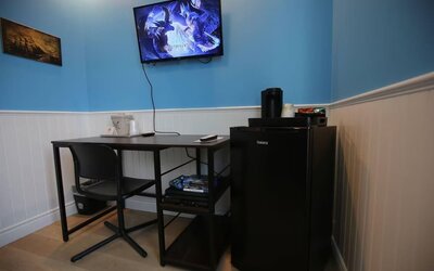 Dedicated guest workspace with desk, mini refrigerator and entertainment area at Hotel Brossard.