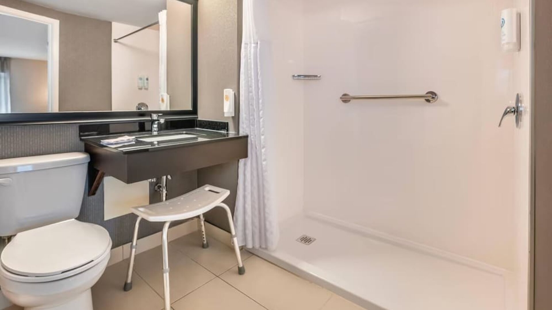 Accessible guest bathroom featuring a roll-in shower, grab bars and convenient accessibility features at Comfort Inn Laval.