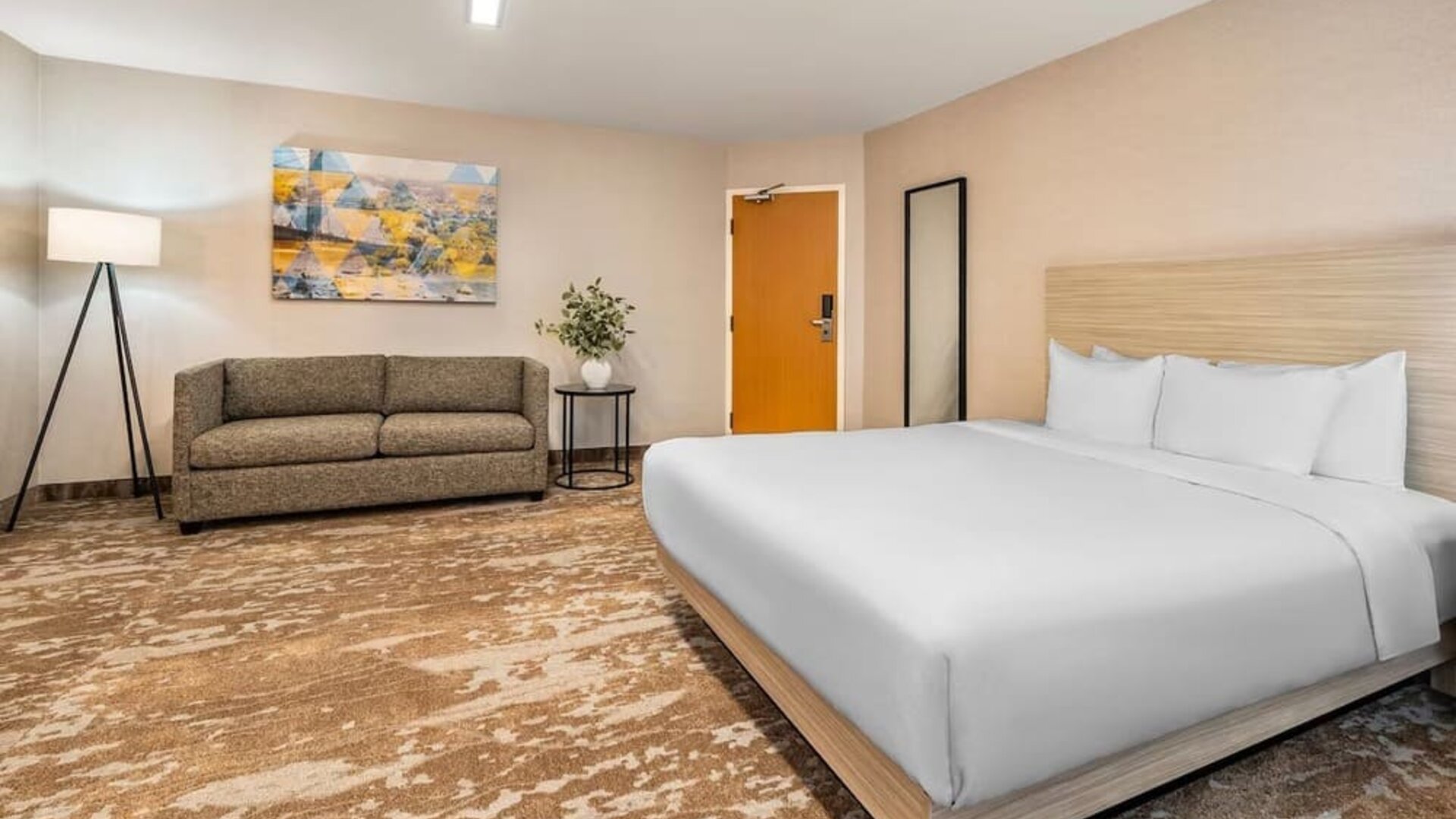 Spacious king guest room with sofa seating and contemporary décor at Comfort Inn Laval.