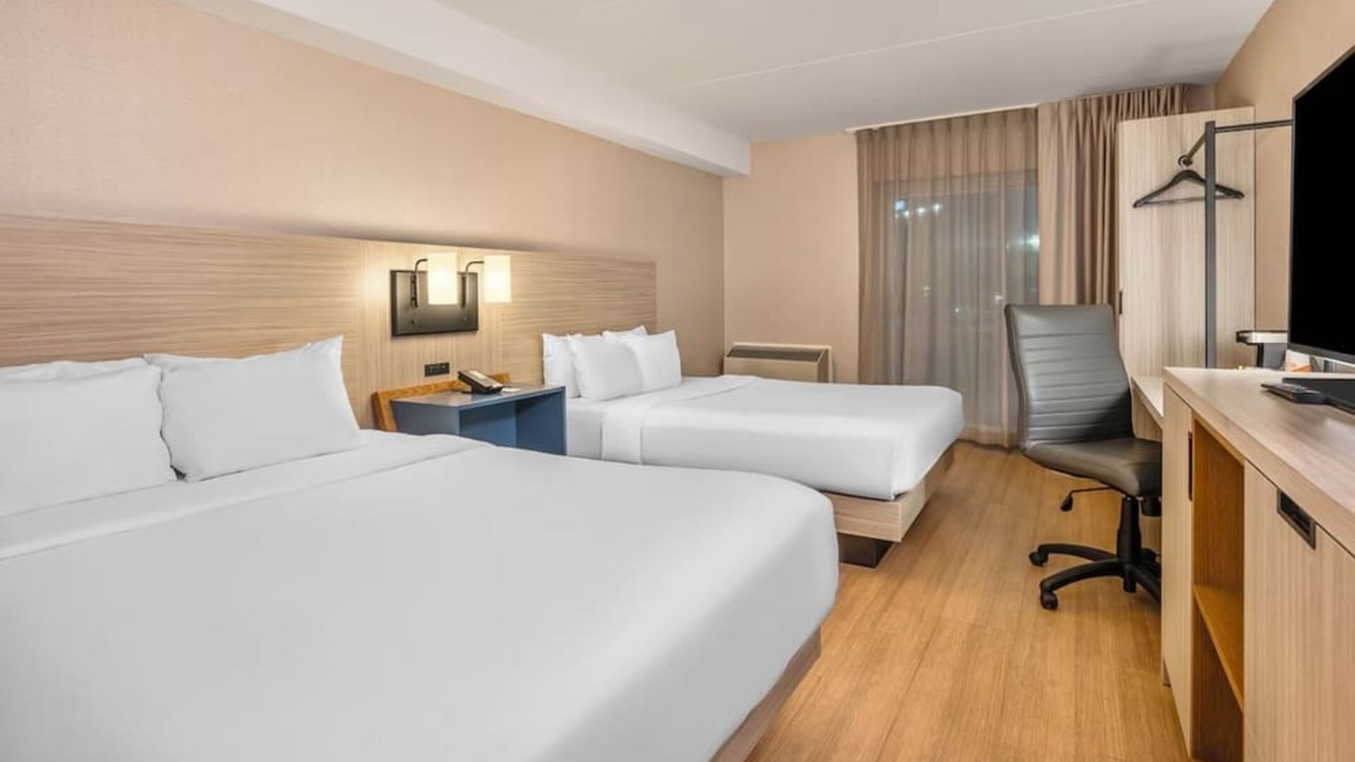 Spacious guest room with two queen beds, work desk and modern furnishings at Comfort Inn Laval.