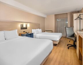 Spacious guest room with two queen beds, work desk and modern furnishings at Comfort Inn Laval.