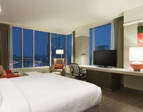 Spacious king guest room with floor-to-ceiling windows, city views, workspace and comfortable seating at Hilton Garden Inn Calgary Downtown.